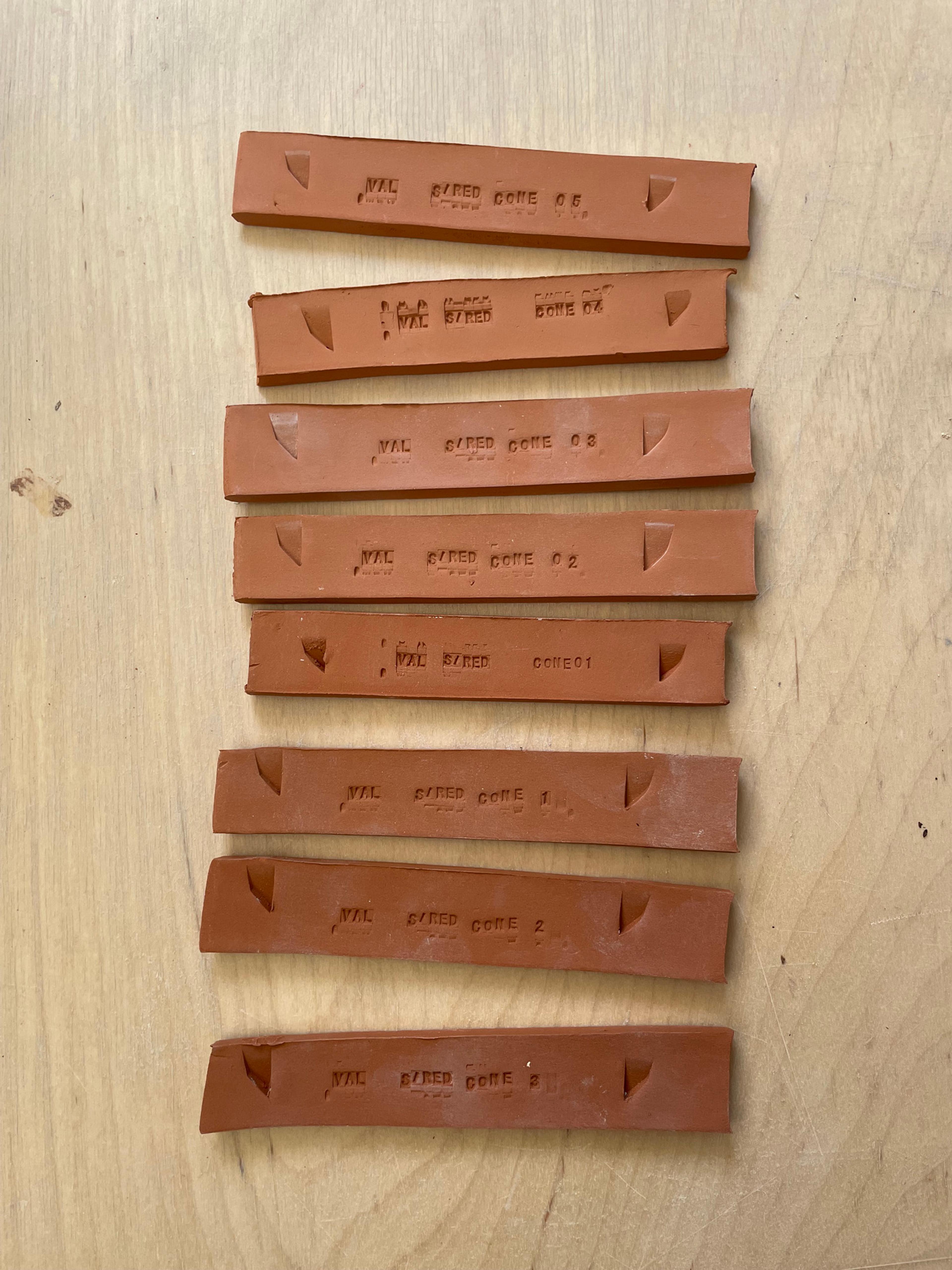 Eight rectangular pieces of fired clay, each stamped with a material reference