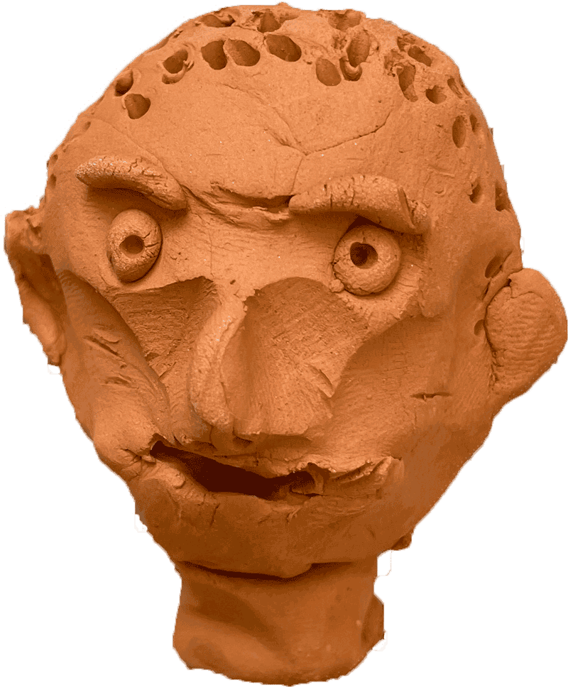 A small clay head sculpture sat on a piece of newspaper