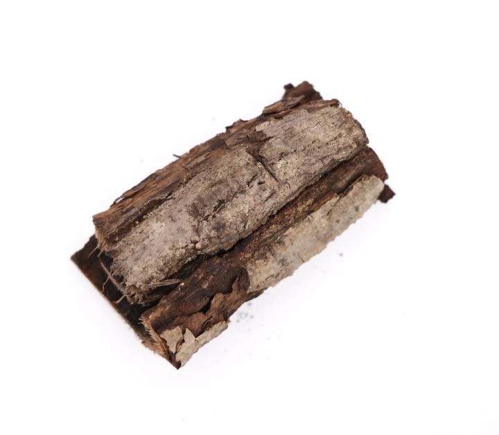 A single log seen close, its bark splitting into shaggy grey-brown plates with pale wood showing through the gaps.