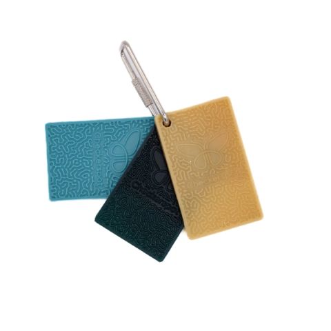 Three rectangular sample chips clipped to a steel carabiner in teal, deep green and mustard, each moulded with a dense maze-like relief pattern and stamped with the Checkerspot name and butterfly mark.