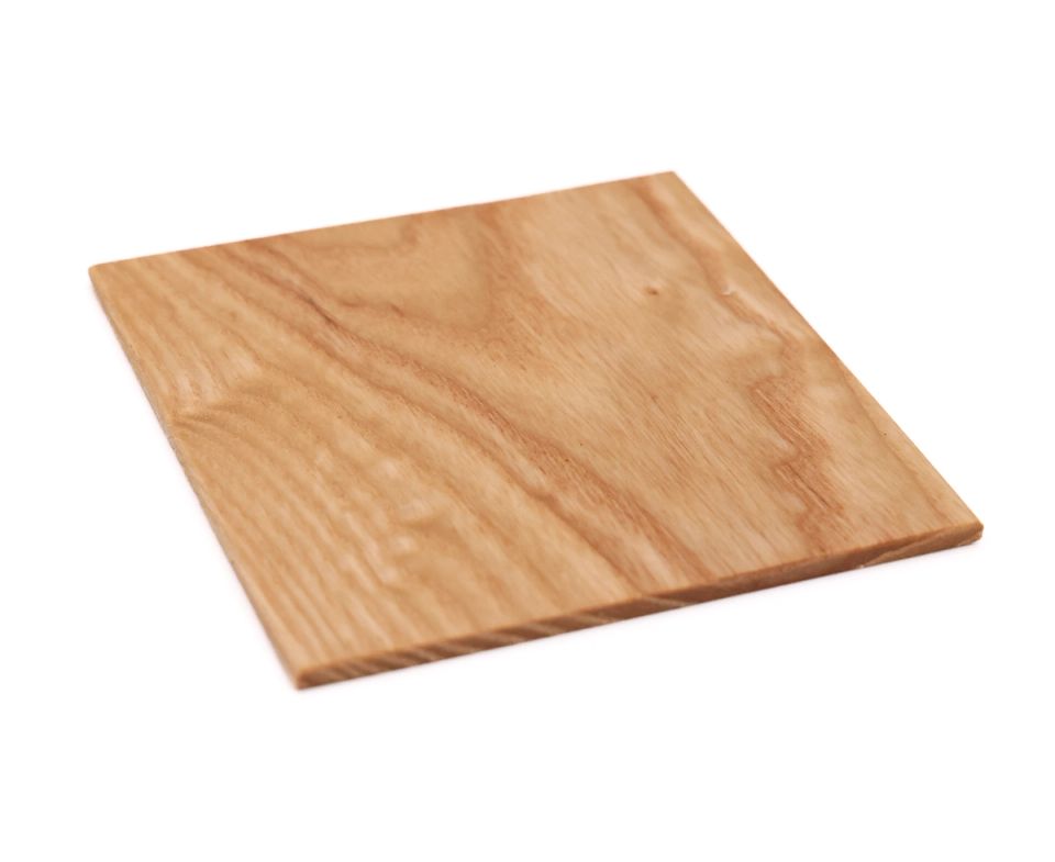The same square tilted at an angle, its planed face catching the light and the thin cut edge visible below.