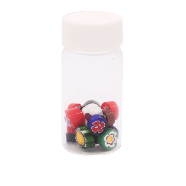 The jar seen capped and from further back, the patterned canes settled at the bottom with their red, green, blue and yellow flower ends visible through the plastic.