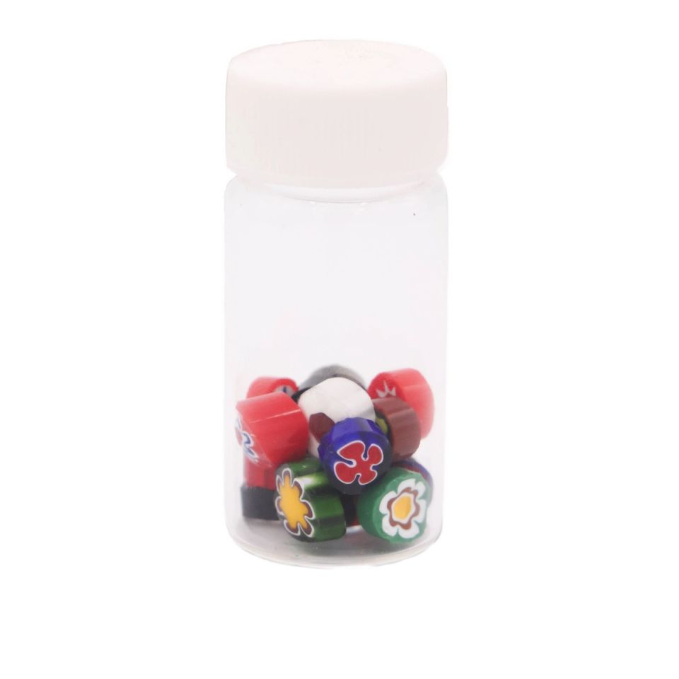 The jar seen capped and from further back, the patterned canes settled at the bottom with their red, green, blue and yellow flower ends visible through the plastic.