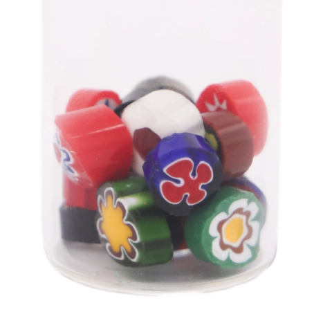 A clear jar packed with short cylindrical glass canes, their cut ends showing flower patterns in red, green, blue, yellow and white.