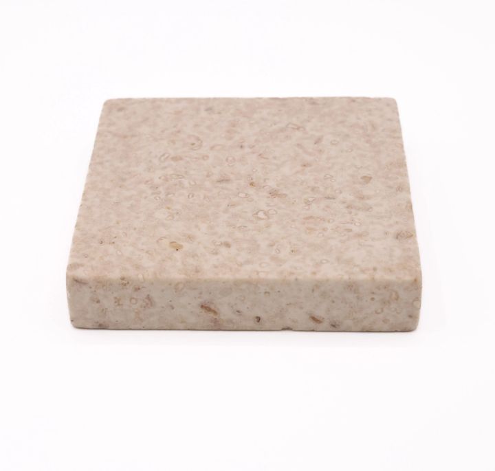 The same tile seen at an angle, showing its considerable thickness and the pitted texture continuing over the edge.