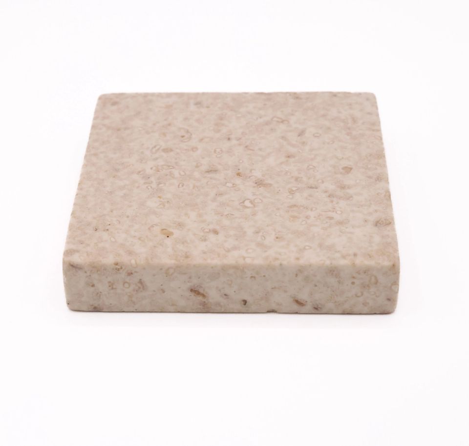 The same tile seen at an angle, showing its considerable thickness and the pitted texture continuing over the edge.