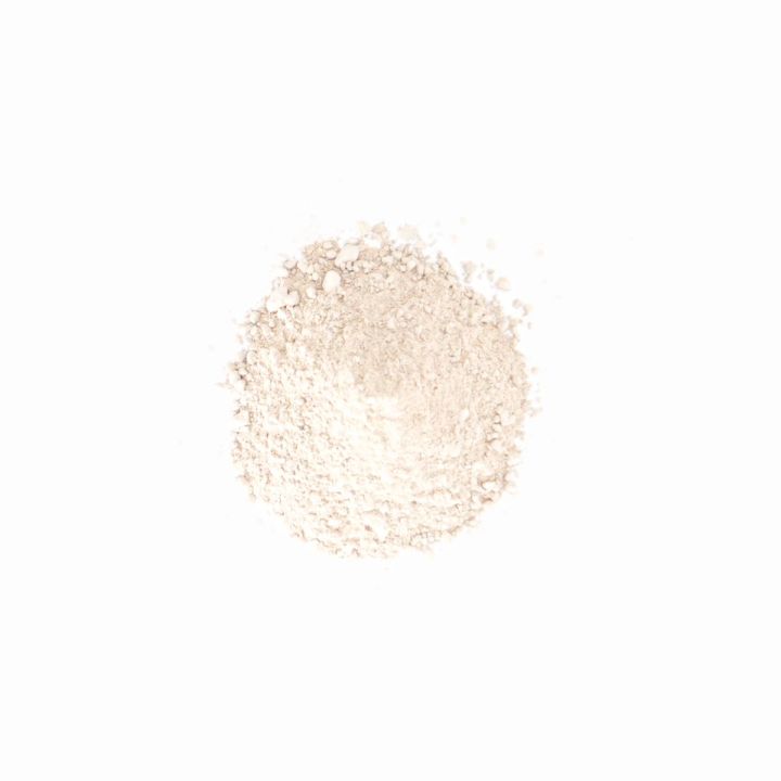 A smaller, much paler heap of the same powder, almost white, finely milled and softly mounded.