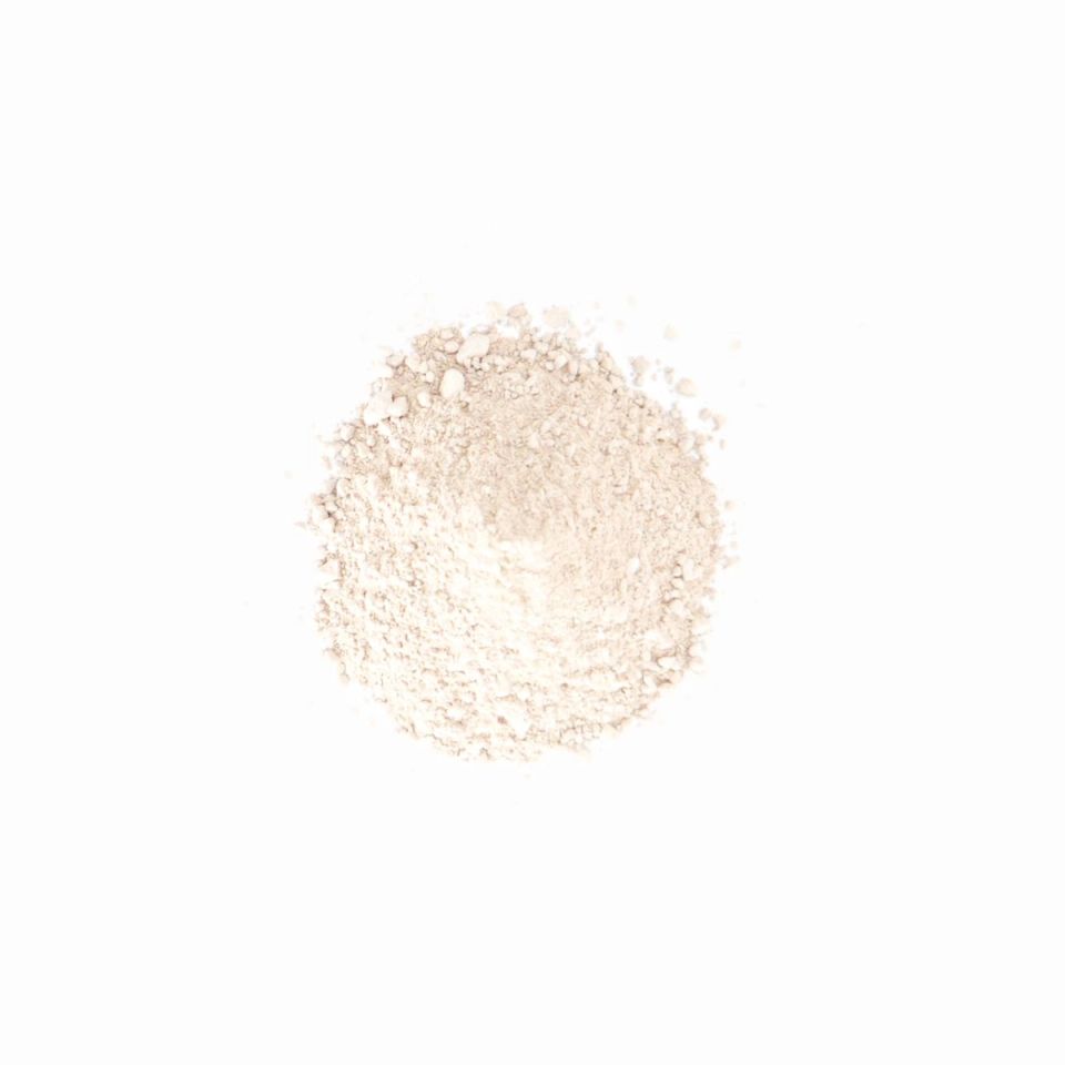A smaller, much paler heap of the same powder, almost white, finely milled and softly mounded.