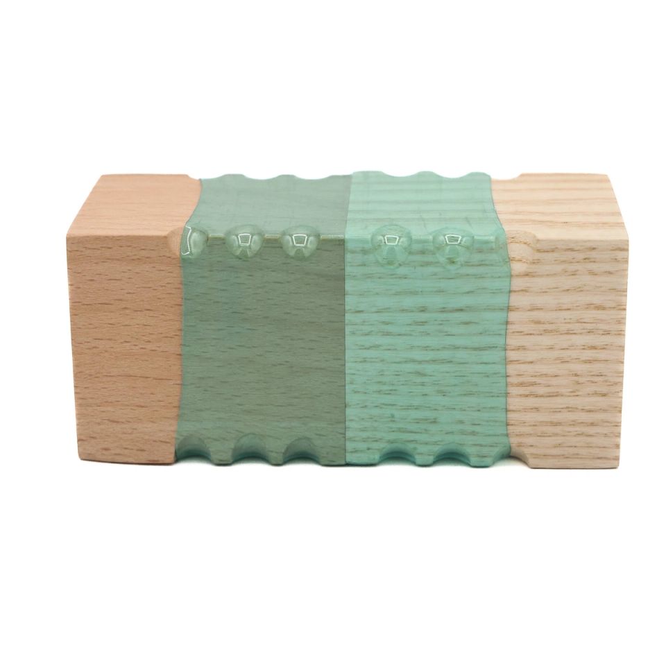 A rectangular block joining pale wood at each end to a mint-green plastic centre, the plastic moulded into fine vertical ridges with a row of small bumps along the top.