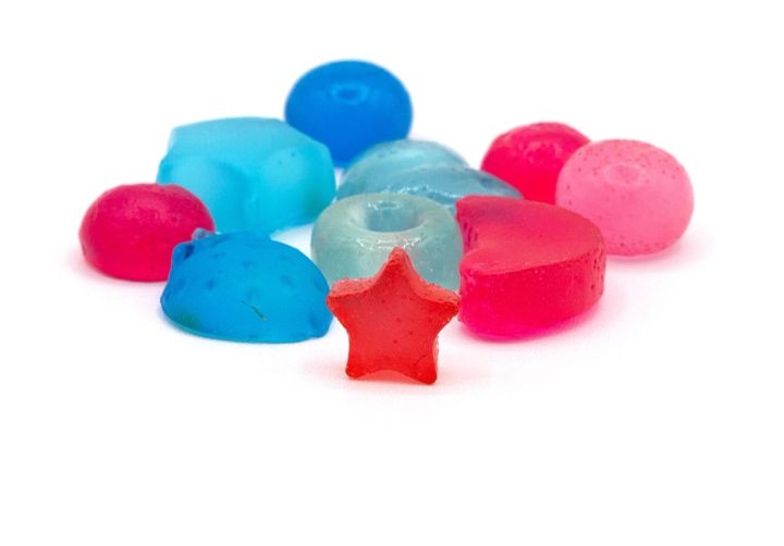 The beads seen closer and fewer, showing their translucency and moulded shapes — a star, a heart, domes and discs in pink, red and blues.