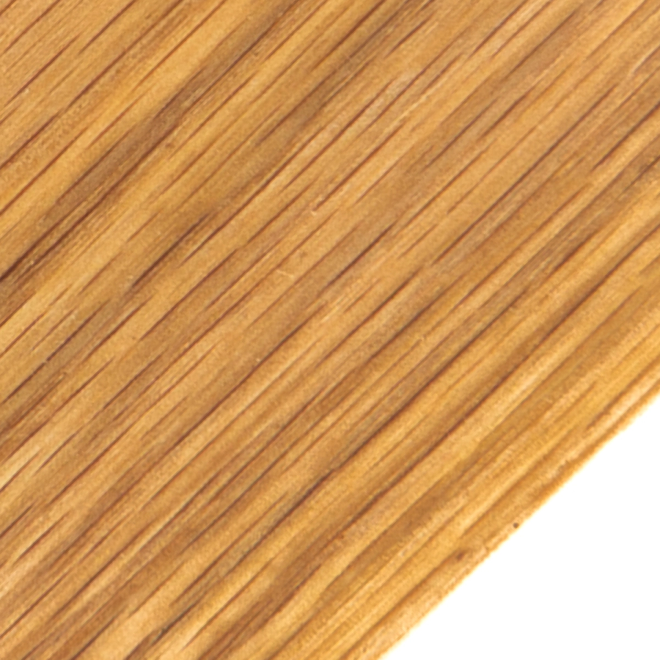 A close view of the grain running diagonally in fine dark lines across warm honey-brown, the board's corner at lower right.