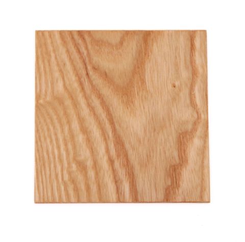 A square of pale golden ash, planed smooth, its grain arching in concentric bands across the face.
