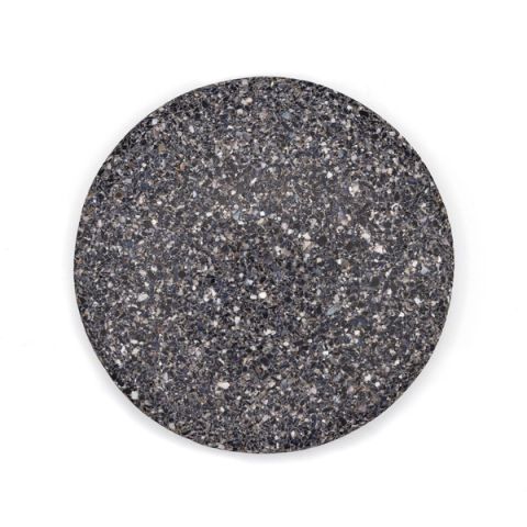 A round tile of dense composite, charcoal grey shot through with pale flecks of crushed shell in white, blue and brown.