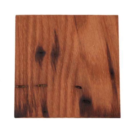 A square of chestnut in deep reddish brown, its surface streaked with dark knots and scorch-like markings, with a few narrow splits near one edge.