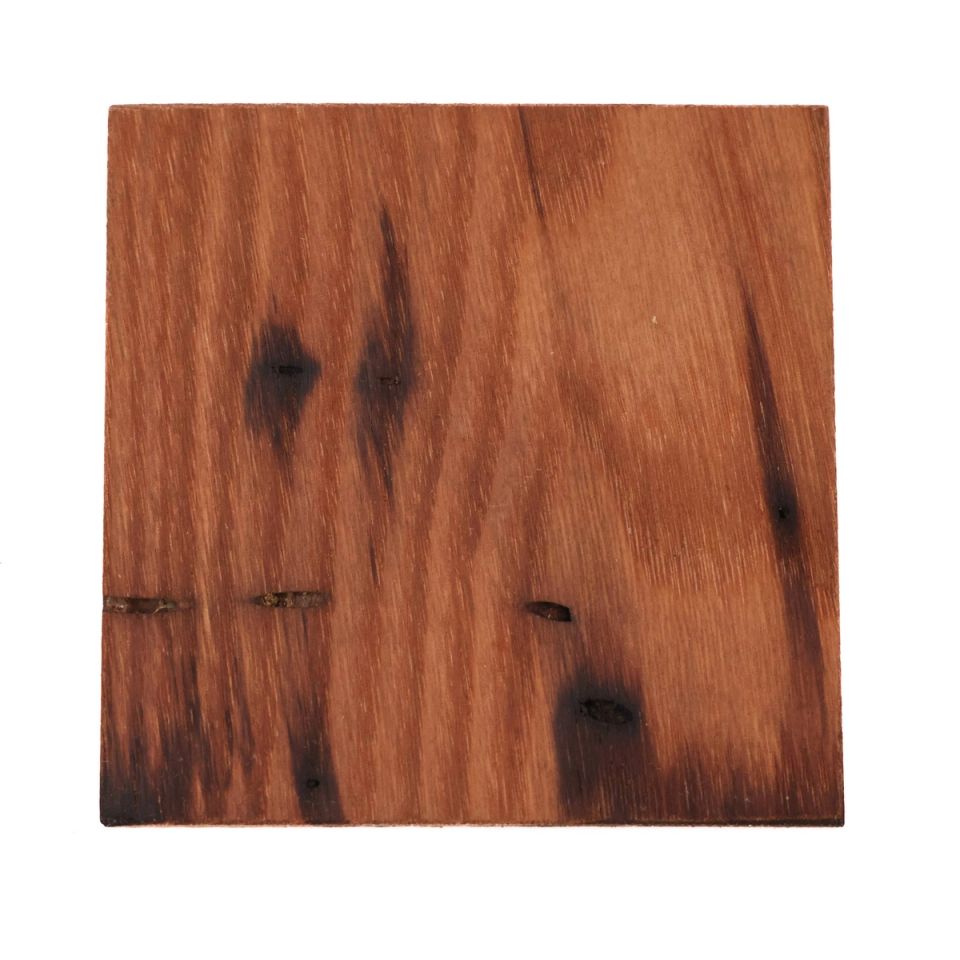 A square of chestnut in deep reddish brown, its surface streaked with dark knots and scorch-like markings, with a few narrow splits near one edge.