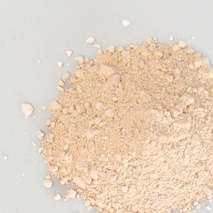 A close view of the same powder, its fine cream grains spilling out into scattered crumbs.