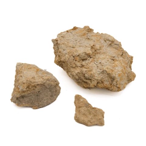 Three rough chunks of dry clay in sandy ochre, coarse and crumbly, their surfaces streaked with darker rust staining.