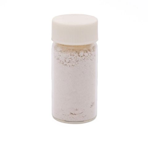 A clear glass vial with a ribbed white screw cap, filled with fine off-white powder that clumps softly near the top and carries a faint sandy tint.