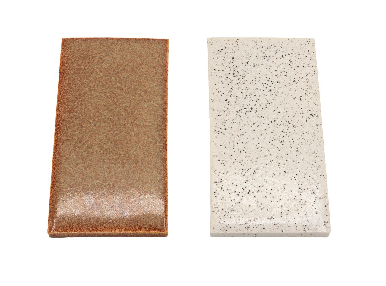 Two rectangular tiles side by side: one glazed in warm coppery brown with a metallic sheen, the other unglazed and speckled cream and grey.
