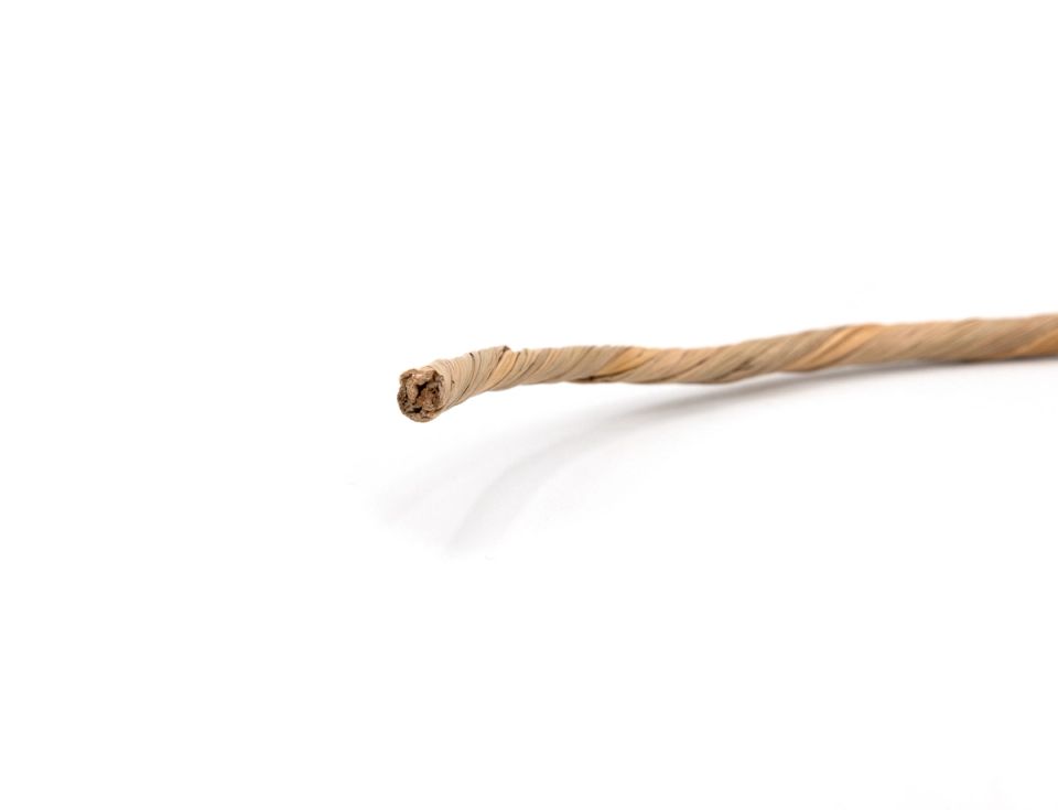 A twisted length of waxed paper cord in pale straw, its spiral wrap loosening into a frayed core at the cut end.