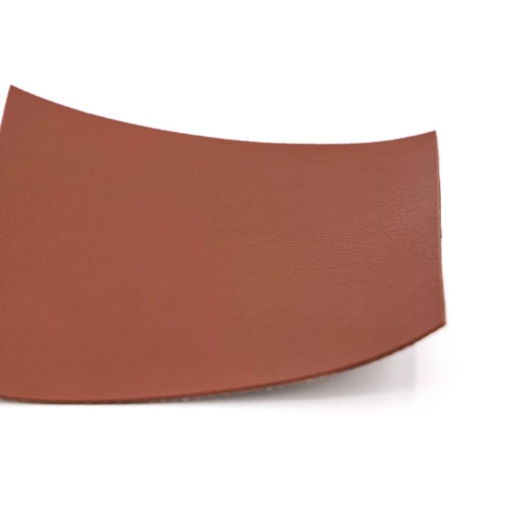 A much larger piece of chestnut-brown leather curving as it flexes, showing how the material drapes at scale.