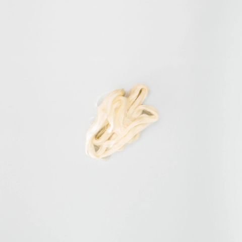 A loose skein of undyed silk in soft ivory, the filaments smooth and lustrous, gathered into a small tangle of loops.
