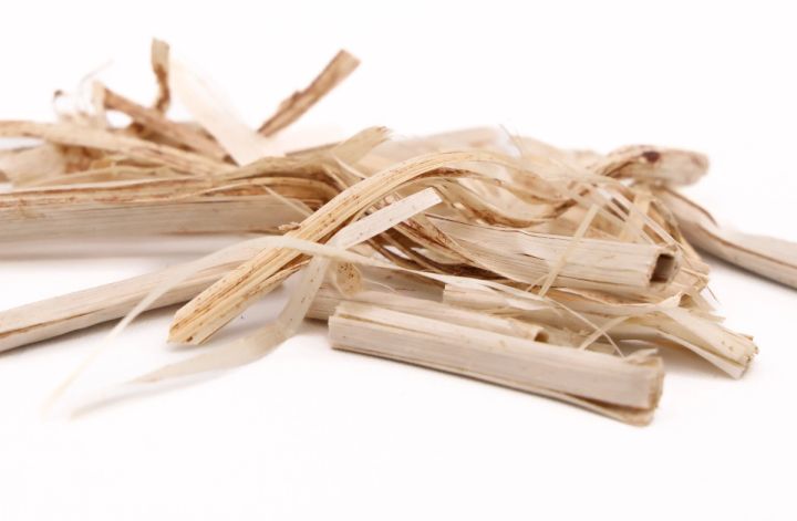 A heap of the fibre seen close, its flat pale ribbons split and splintered into coarse strips.