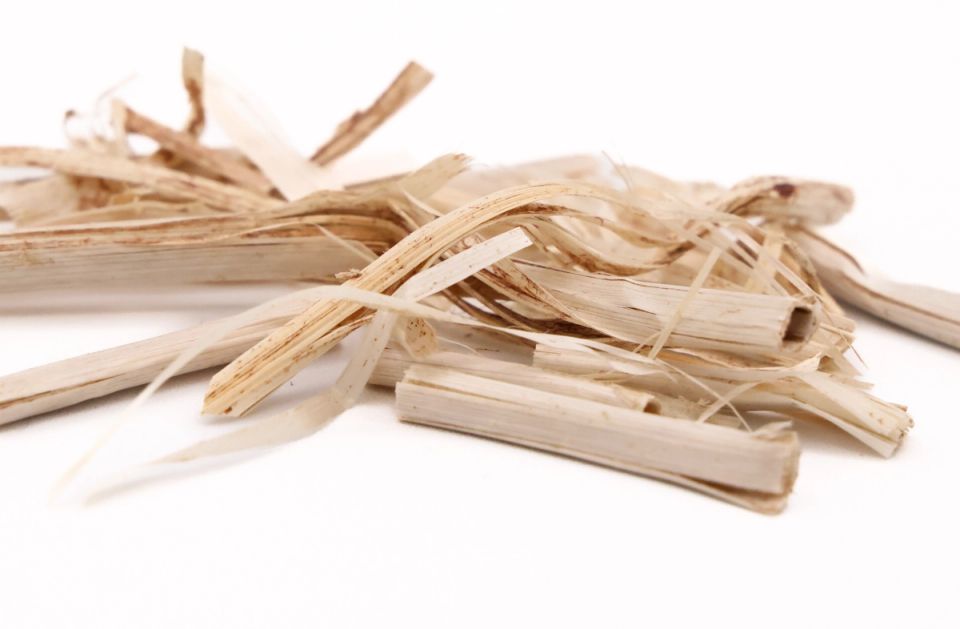 A heap of the fibre seen close, its flat pale ribbons split and splintered into coarse strips.