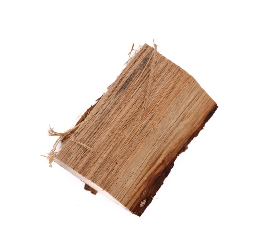 A block of white oak seen at an angle, its face showing tight straight grain in warm tan with a darker split at the top and frayed fibres at one corner.
