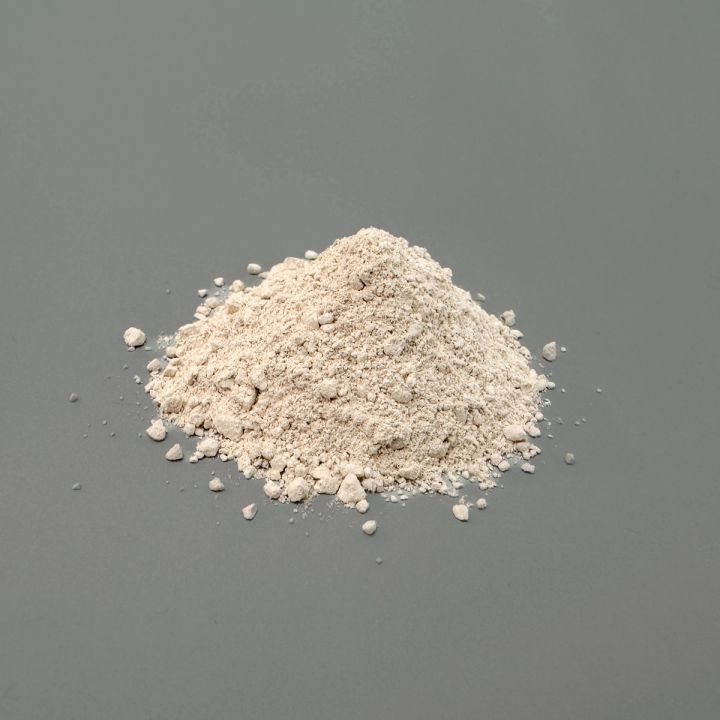 A small heap of pale cream porcelain powder, finely milled with coarser lumps around the base.