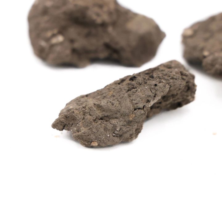 A close view of the clay lumps, their coarse grey surfaces studded with pale grit and small dark inclusions.