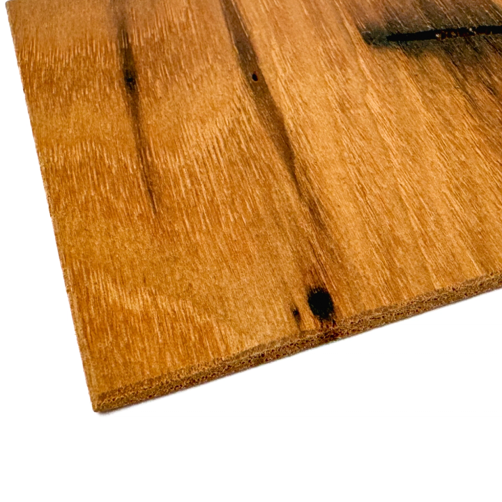 A close view of one corner, showing the deep dark knots, a small bore hole, and the layered edge of the board.