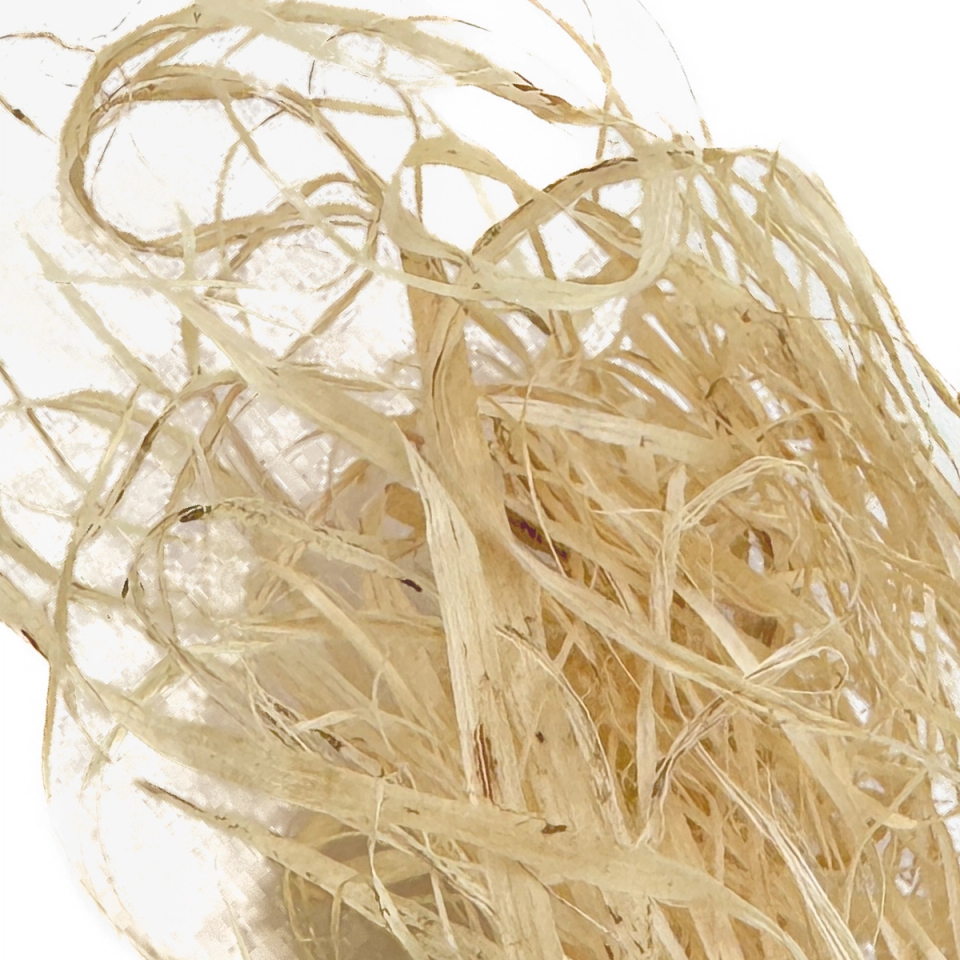 A loose mass of pale straw-coloured kudzu fibre, long flat ribbons twisting into wide loops with finer strands splitting away.