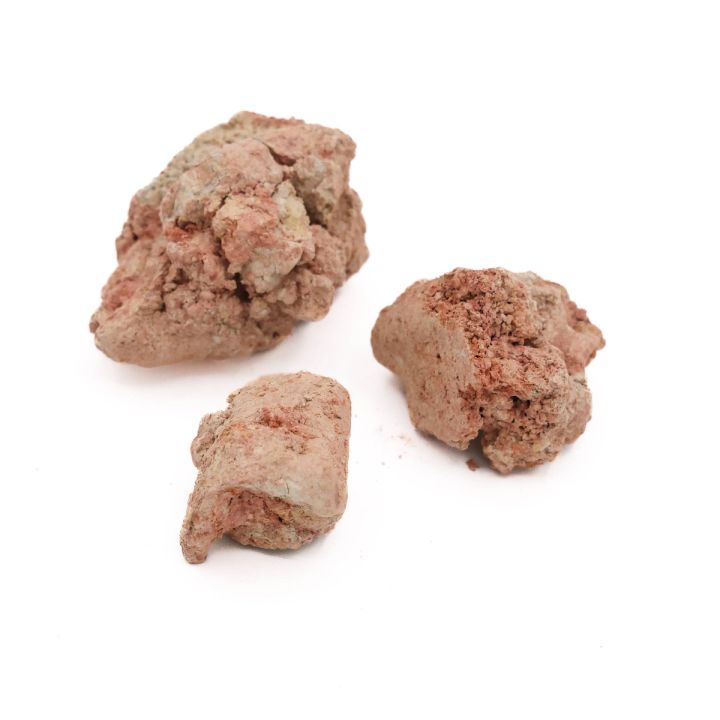 Three lumps seen closer, their surfaces mottled pink and cream with crumbling broken faces.