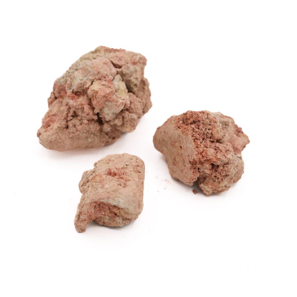Three lumps seen closer, their surfaces mottled pink and cream with crumbling broken faces.