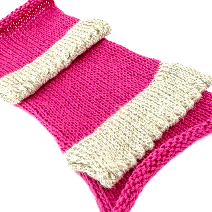 A close view of the knitting, the cream bands' looser ribbed structure standing out against the tight magenta knit.