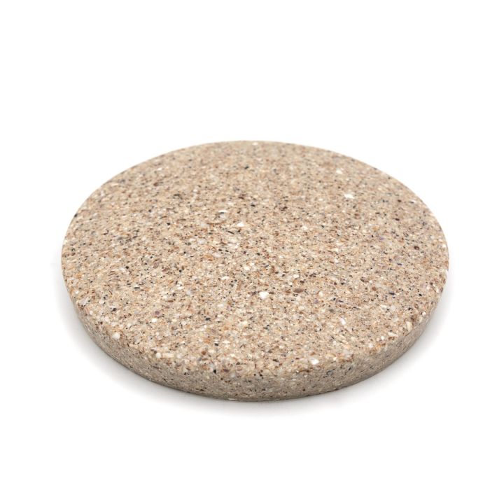 The tile at a low angle, its speckled face foreshortened and the full thickness of the edge visible.