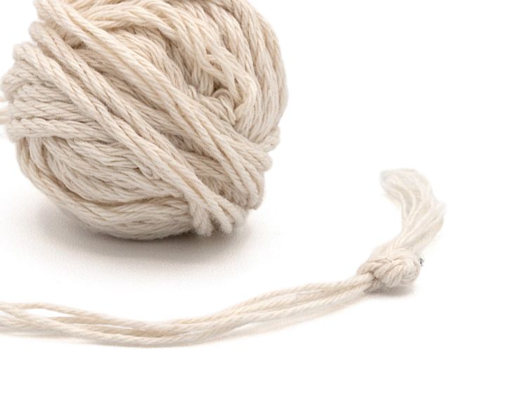 The ball seen closer, the plied strands distinct where they wrap the surface and the loose end knotted.
