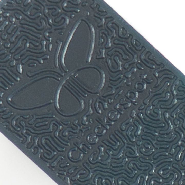 A close view of one chip in deep teal, the maze-like relief pattern filling the frame around an embossed butterfly and the Checkerspot wordmark.