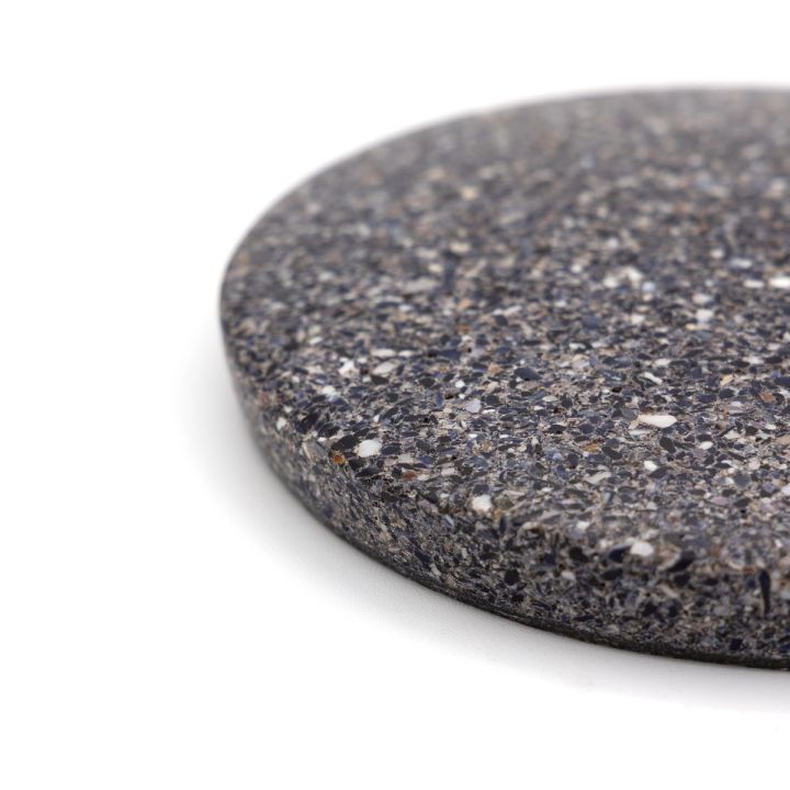 A close view of one edge, the crushed shell fragments large and distinct in white, blue-grey and brown against the dark matrix.