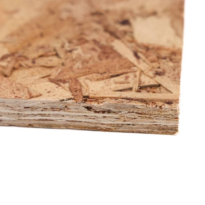 A close view of the board's corner, the pressed chips large and overlapping across the face with the layered edge visible below.