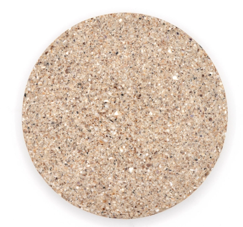 A round tile of dense composite in warm sandy beige, thickly studded with crushed shell in cream, white and grey.