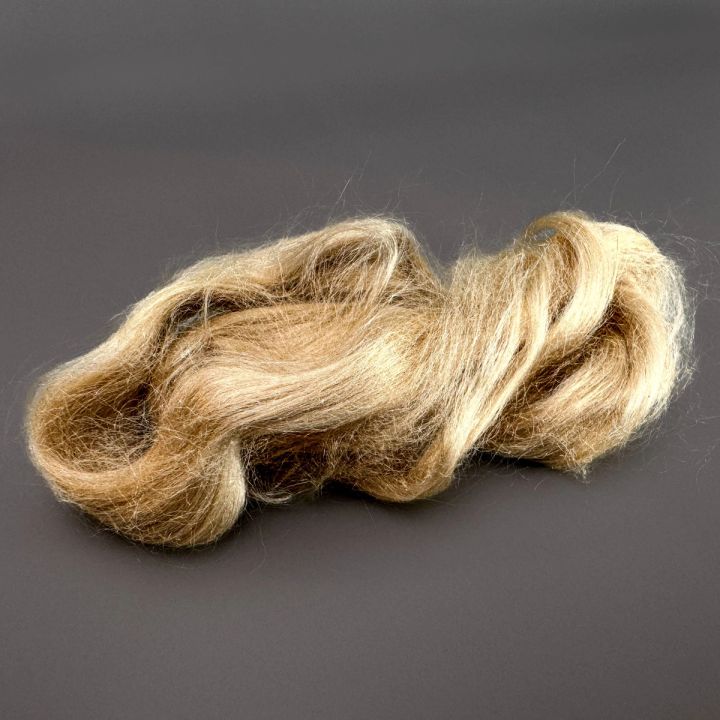 The silk against a dark ground, its honey-gold filaments drawn into deep waves with a strong lustre along each ridge.