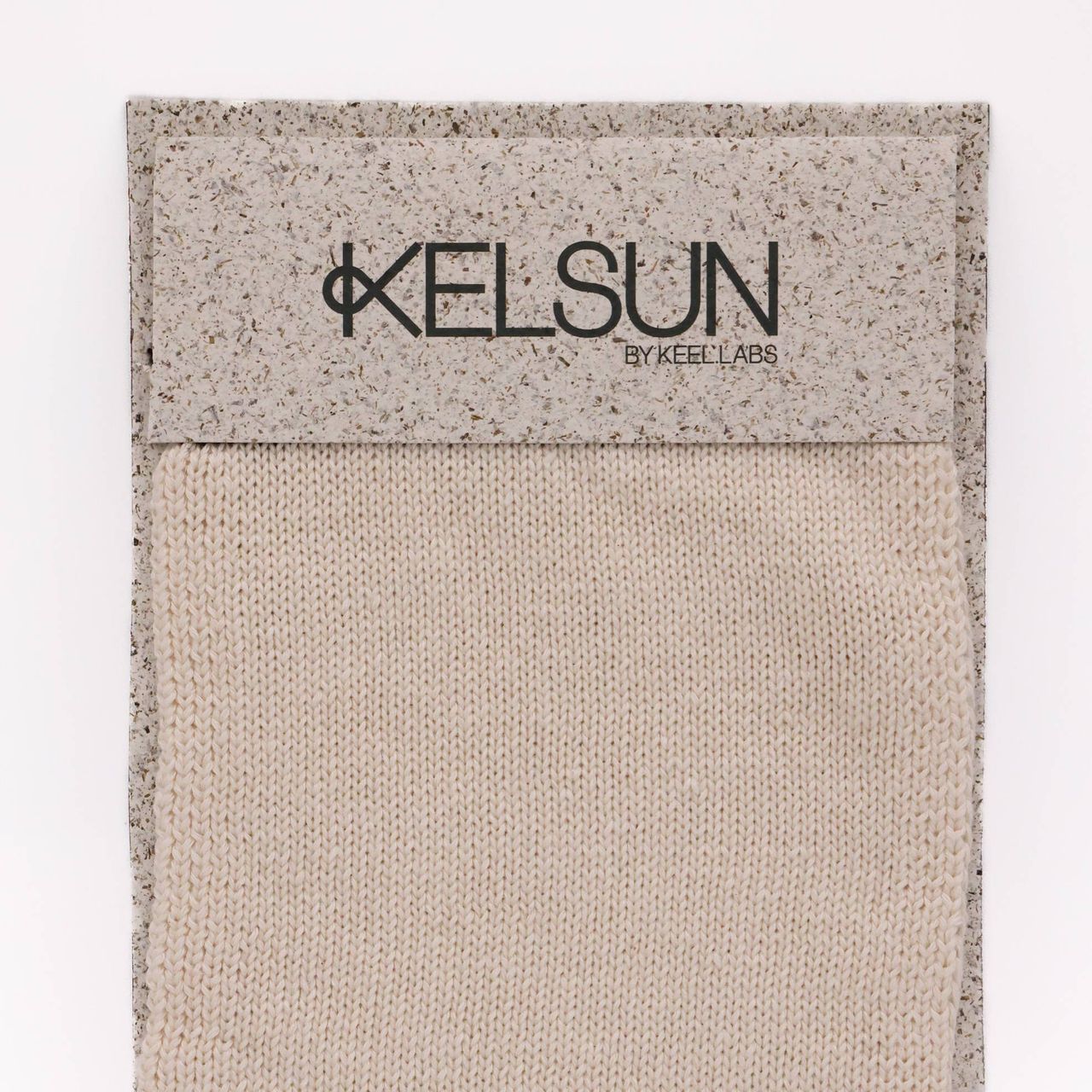 A knitted swatch in undyed cream, stocking stitch running vertically, mounted on a speckled grey board printed “KELSUN by Keel Labs”.