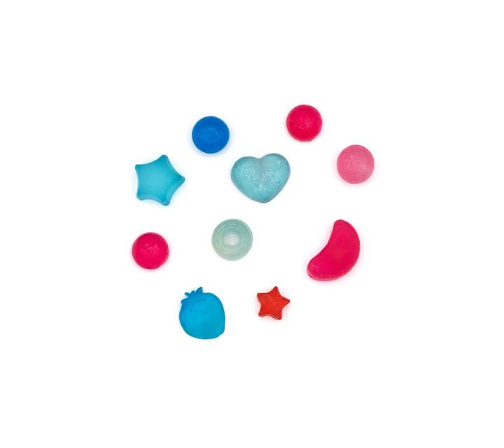 The beads laid out separately and spaced apart, each shape distinct: star, heart, ring, berry and several rounds in pink, red and blue.
