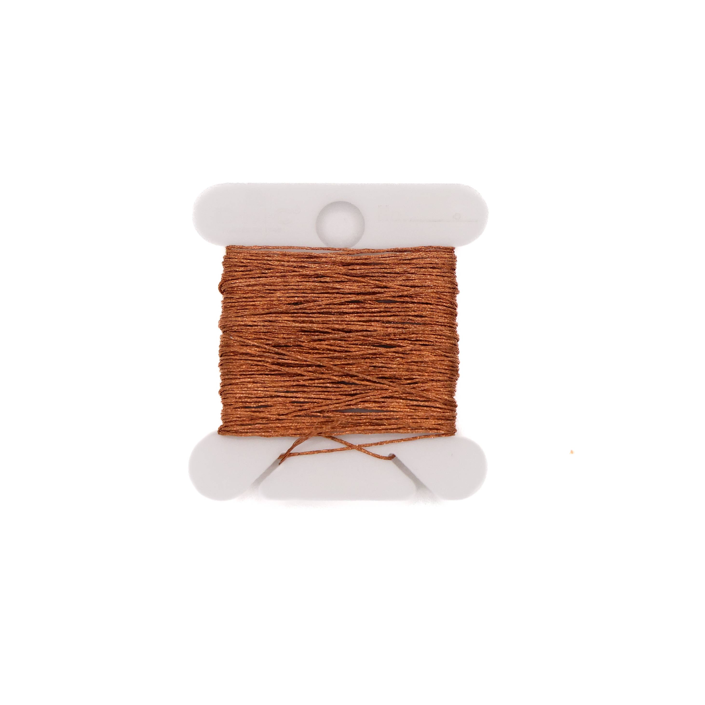 Fine copper-brown thread wound in dense even rows on a white plastic bobbin, a loose end trailing across the bottom.