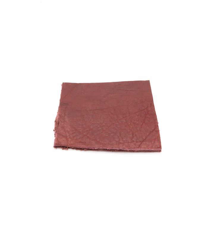 A square of vegetable-tanned cowhide in dusty brick red, its surface finely veined with a natural grain.