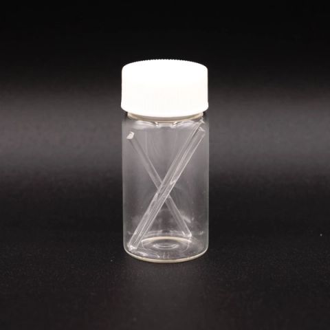 A clear glass vial with a white screw cap holding two fine glass rods crossed inside it.