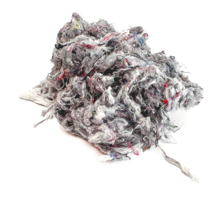 The clump seen whole, grey and matted with red and black threads showing through and a long strand trailing from one side.