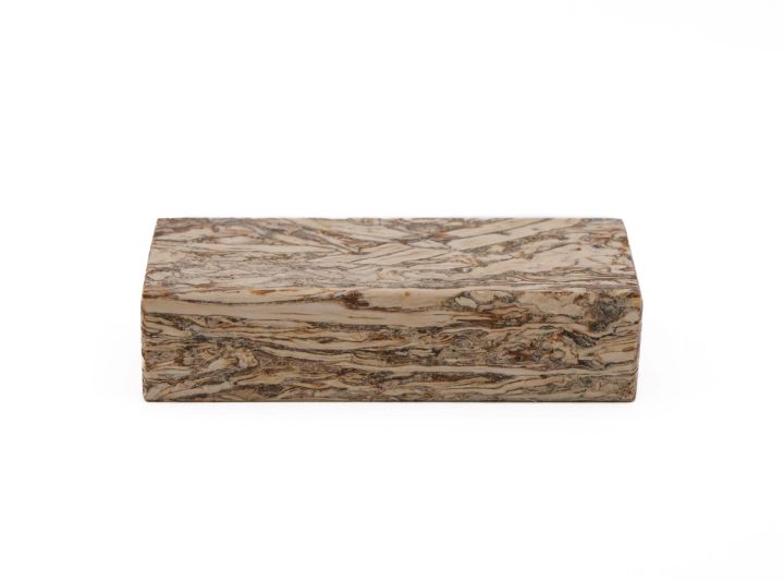 The block from a low angle, the marbled cream-and-brown fibre wrapping from the top face round the long edge.